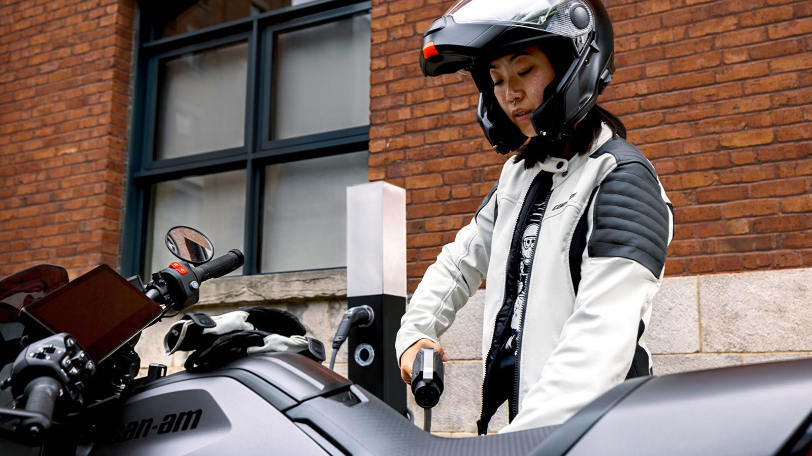 Femme s'apprêtant à recharger sa moto électrique