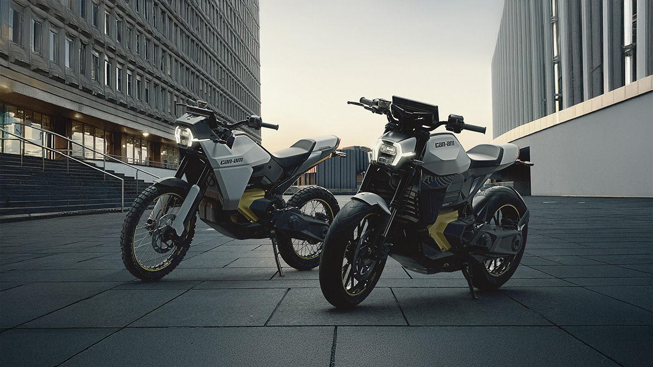Two Can-Am electric motorcycles parked near a huge building in the city