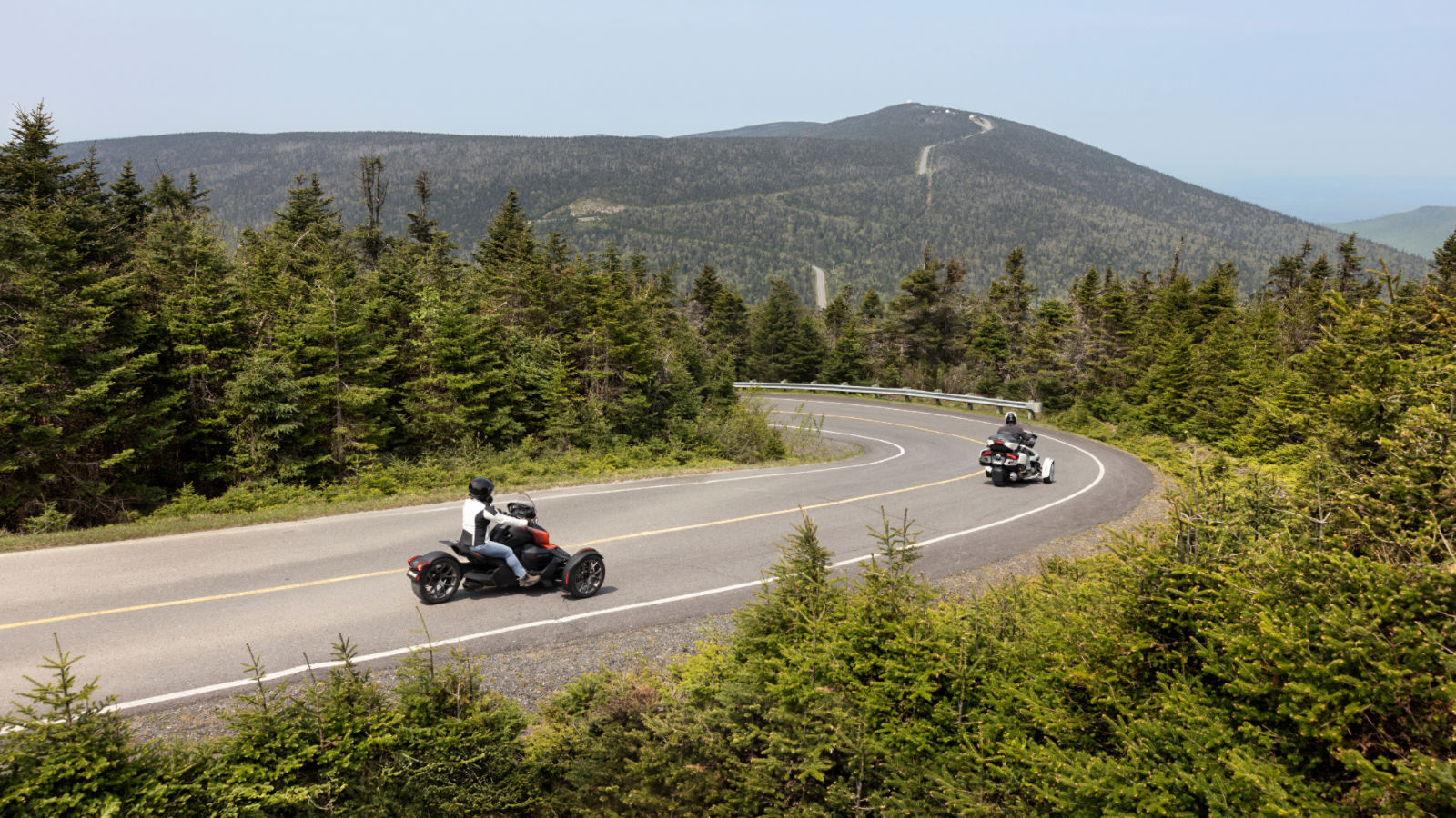 Two Can-Am 3-wheel motorcycle riding down a hill