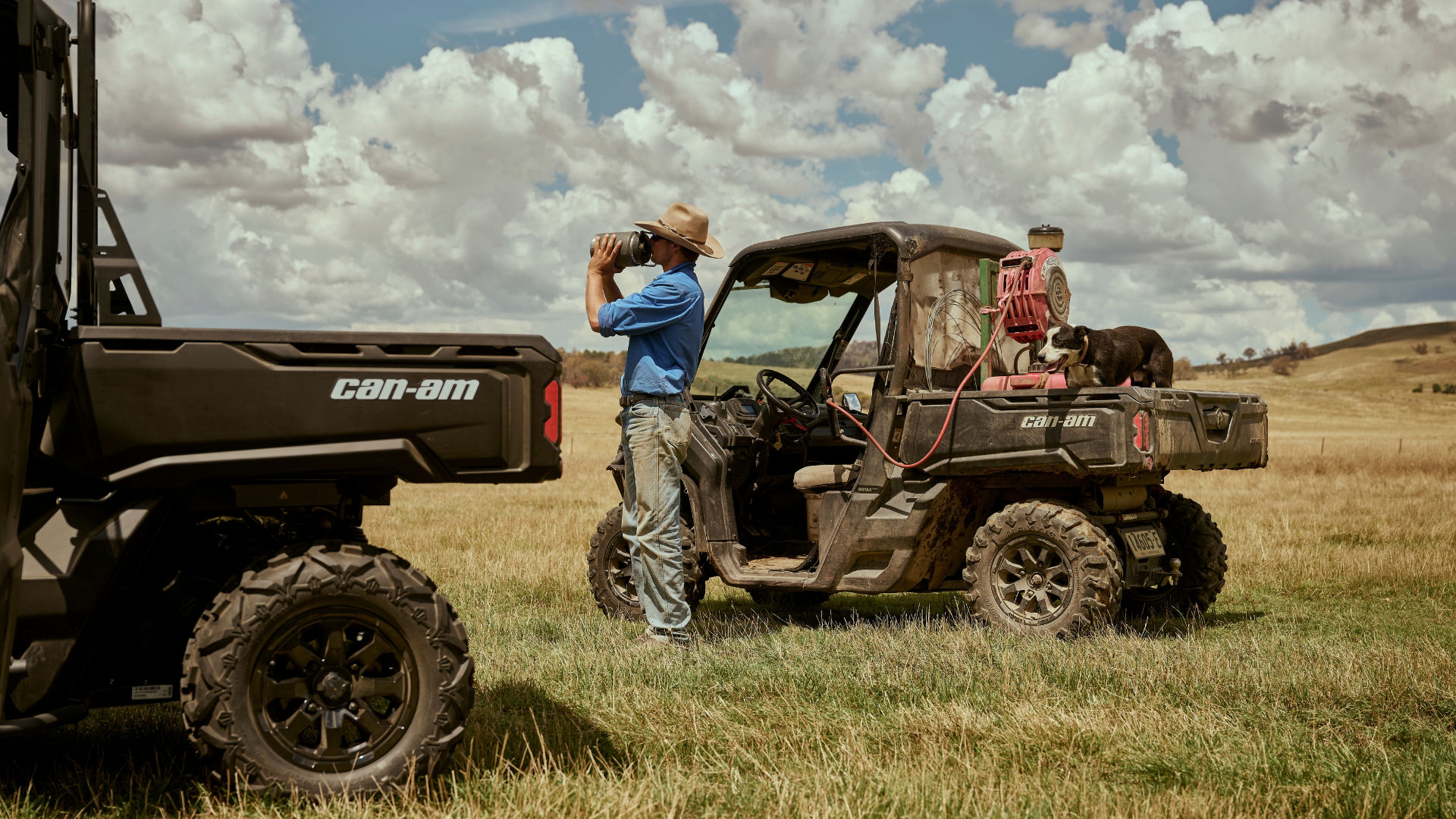 Farmer standing next to a Can-Am Defender having a drink of water.