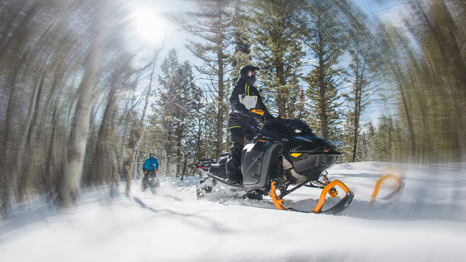 Deux motoneigistes en randonnée dans une forêt enneigée sur leur Ski-Doo