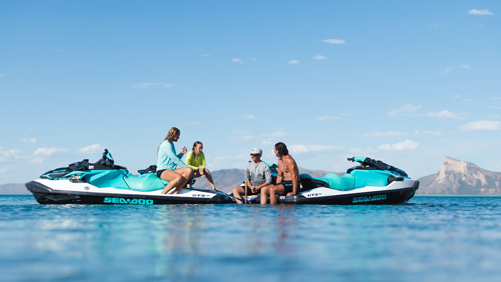Des amis discutant assis sur des motomarines Sea-Doo dans le milieu d'un plan d'eau