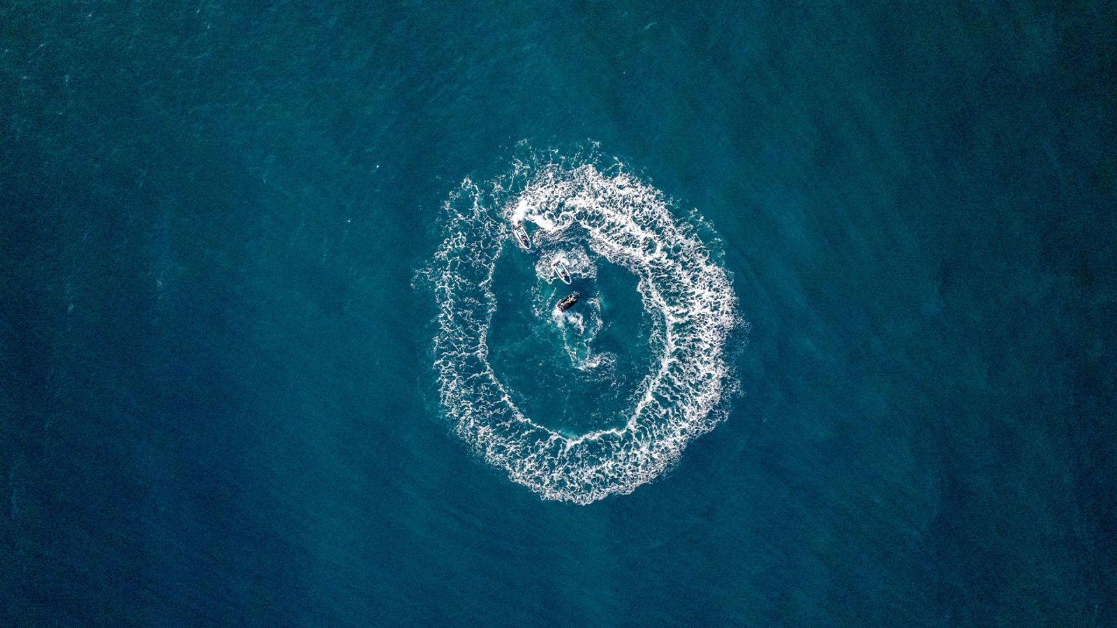 Trois motomarines Sea-Doo faisant des cercles sur l'eau