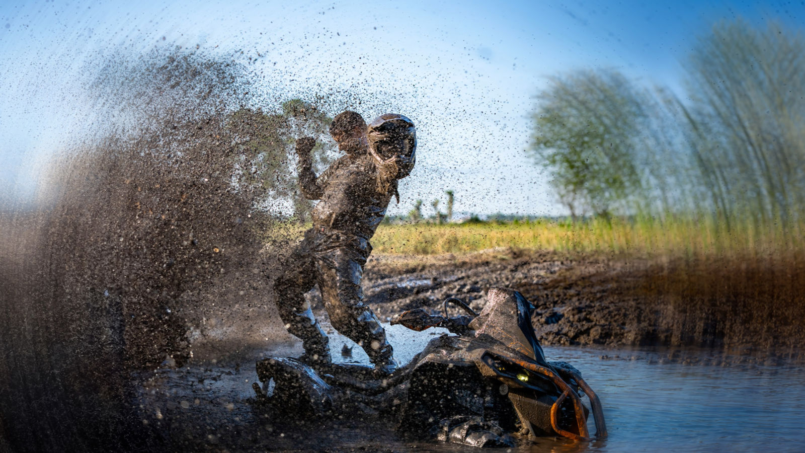 Homme debout sur un VTT de Can-Am couvert de boue