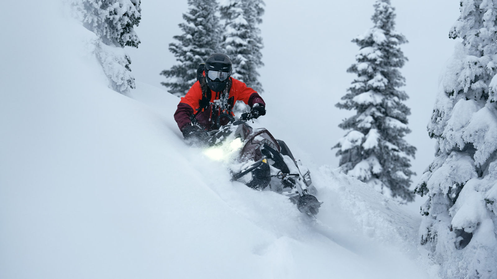 Homme descendant une montagne enneignée sur une motoneige Ski-Doo