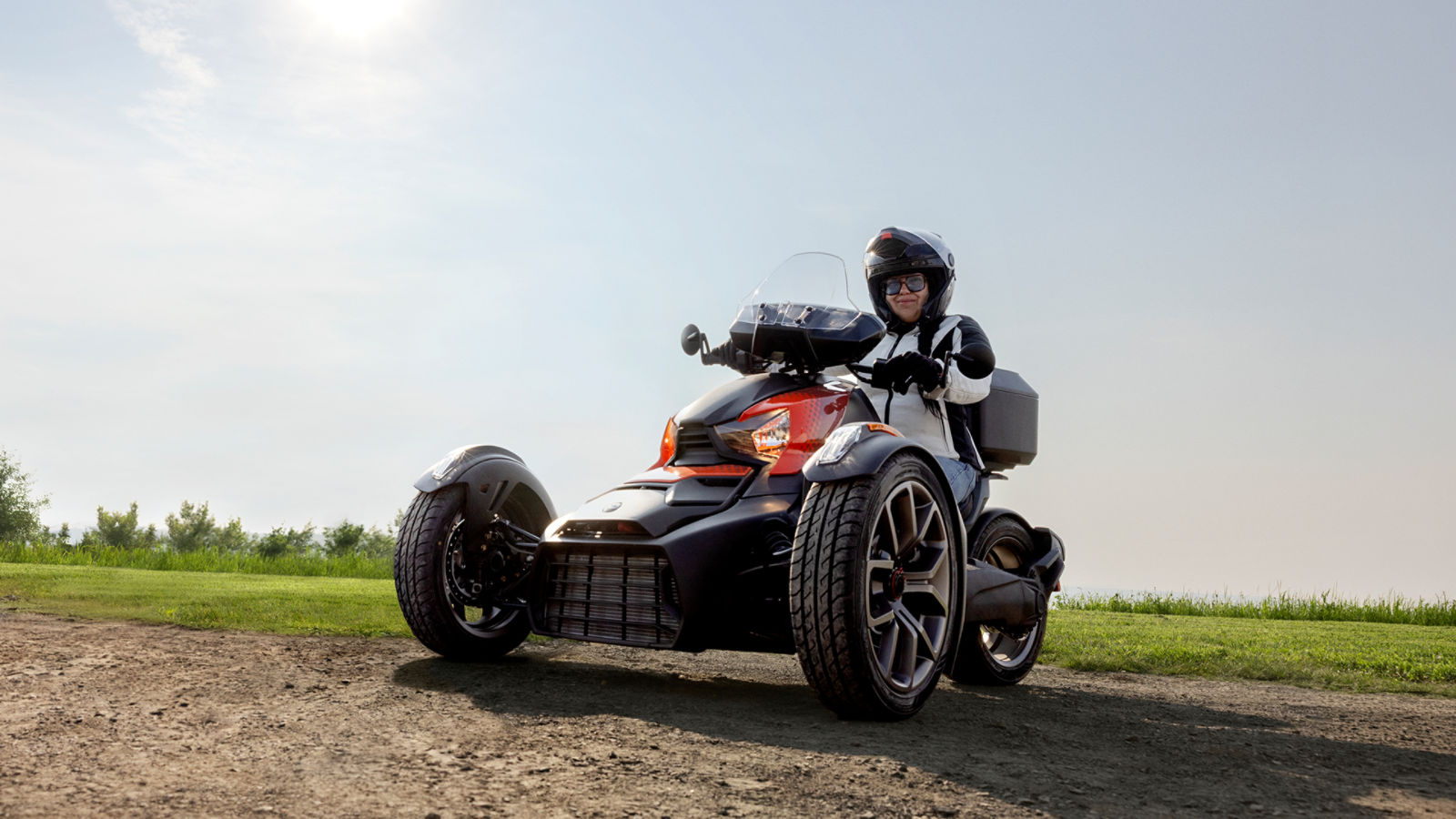 A woman on her parked Can-Am Ryker three-wheeled motorcycle