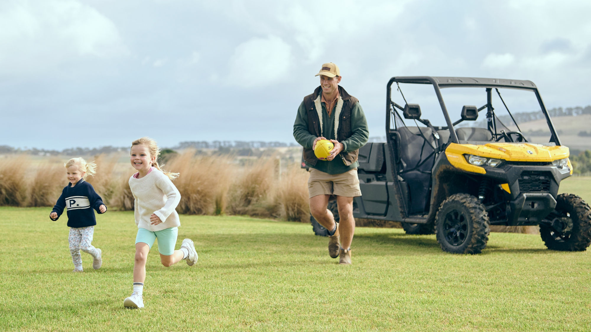 Tom Hawkins kicking a football with his children.