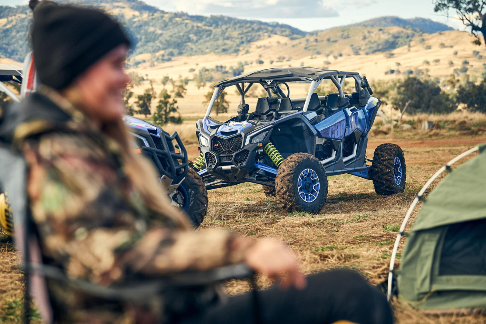 Um UTV Can-Am Maverick X3 MAX rs de 4 lugares perto de alguém em uma cadeira de camping