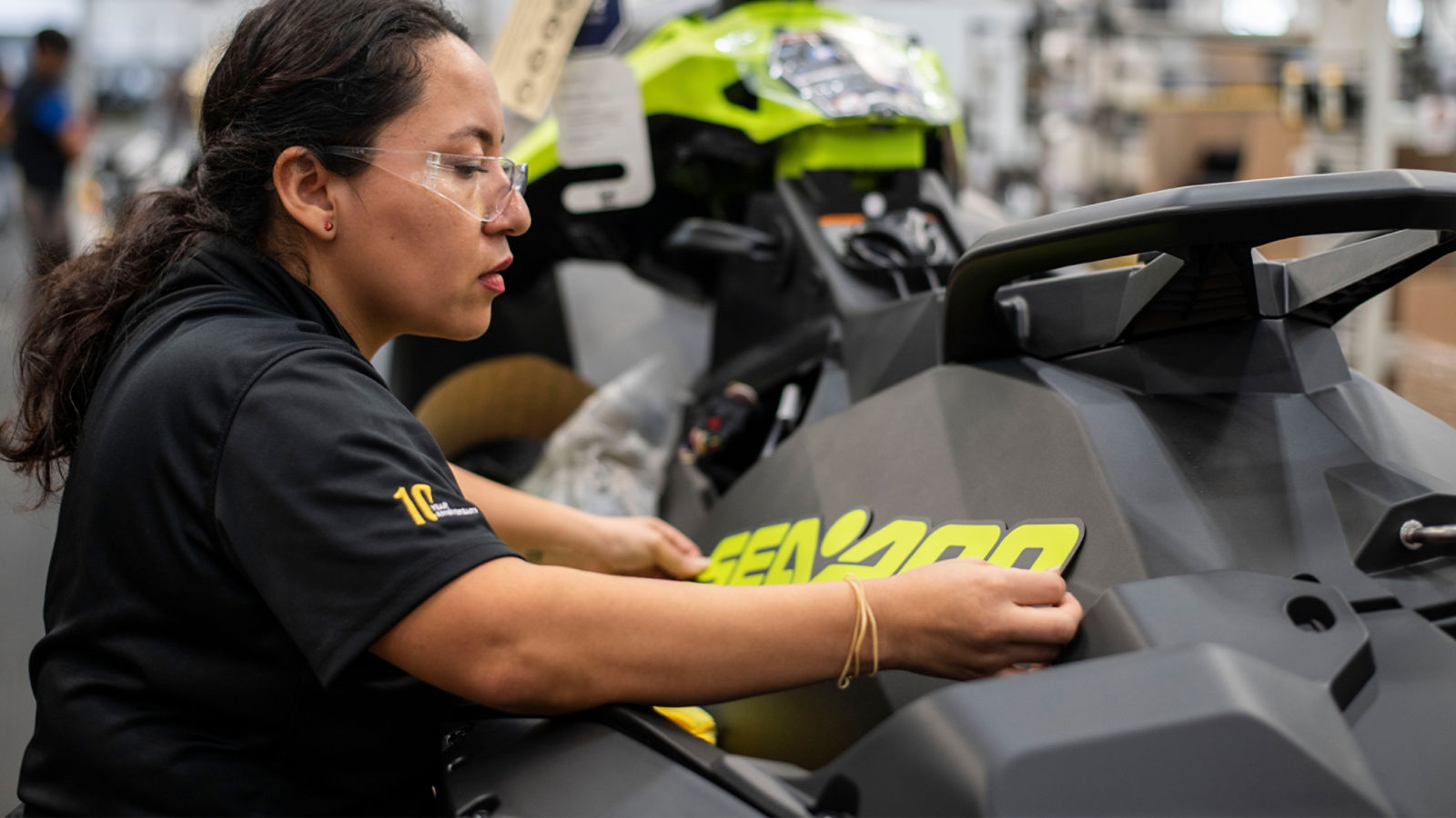  Woman placing the Sea-Doo label on a personal watercraft	