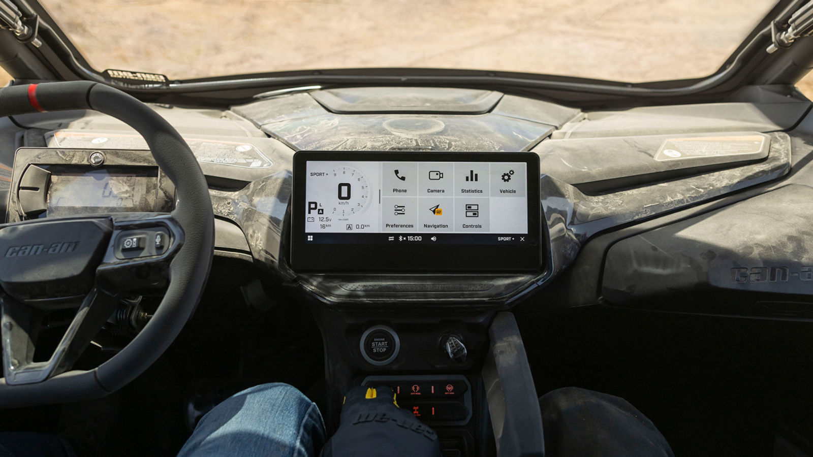 Interior of a Can-Am side-by-side with a digital touchscreen and steering wheel with integrated buttons.