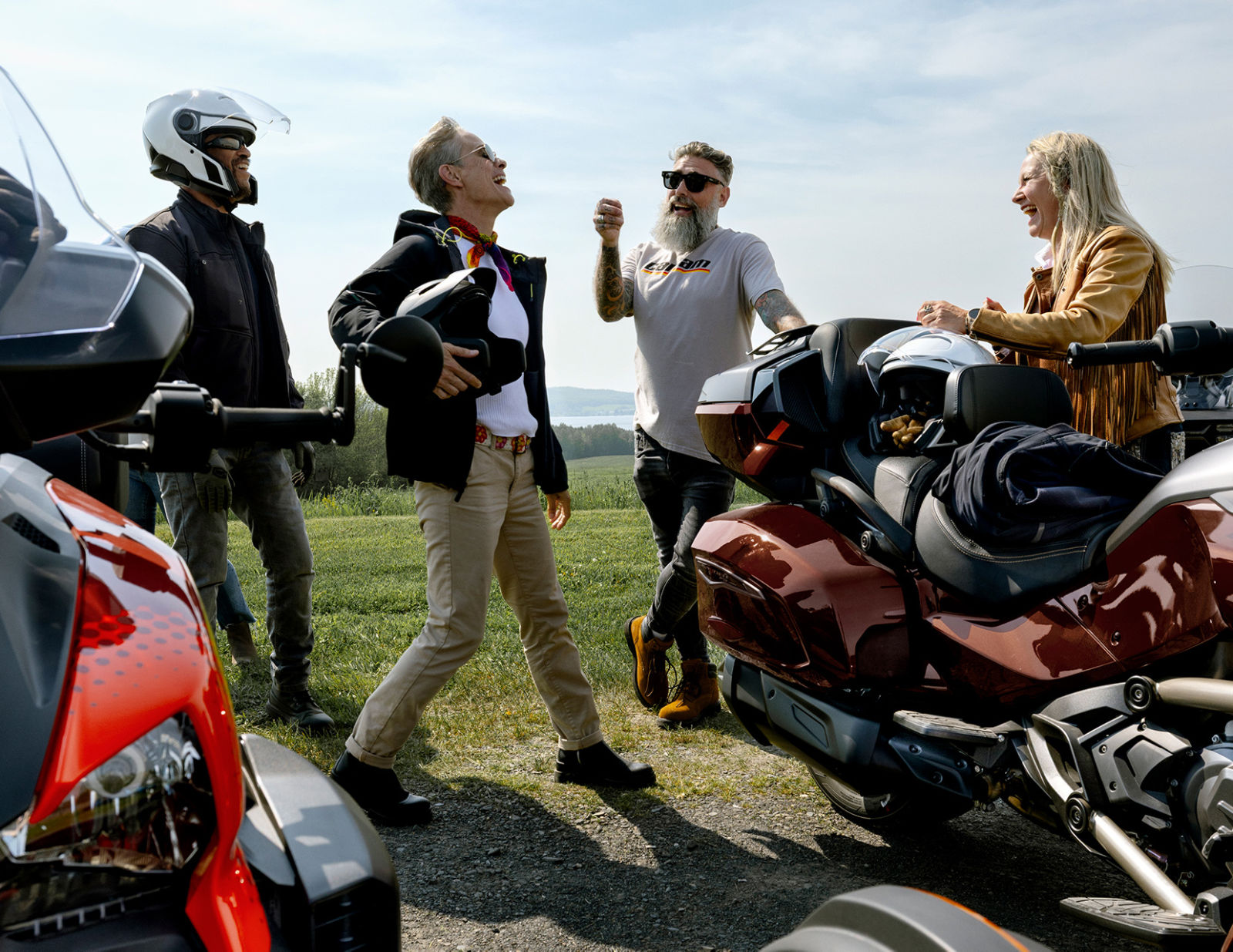 A group of smiling friends, next to their Can-Am three-wheelers 