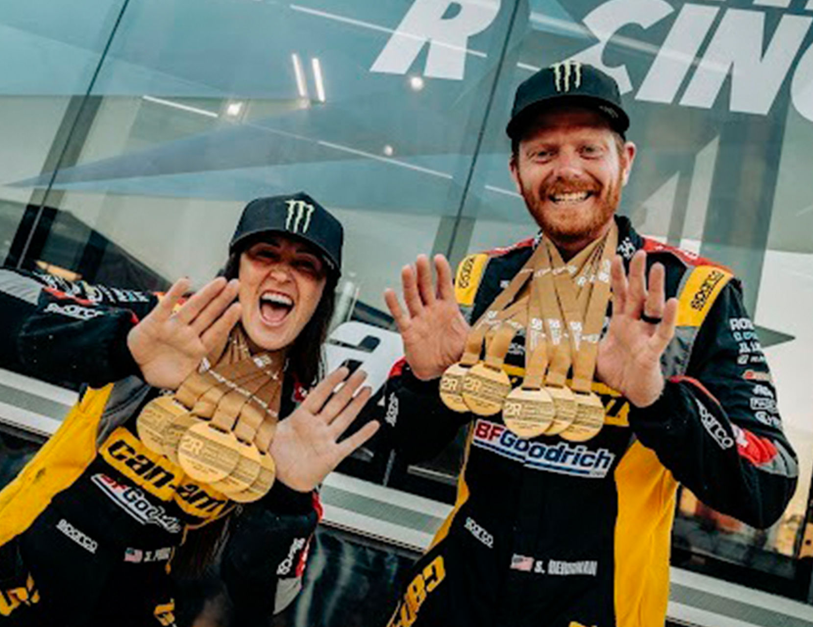 Two Can-Am racing drivers showing off all the medals they won at the Dakar Rally