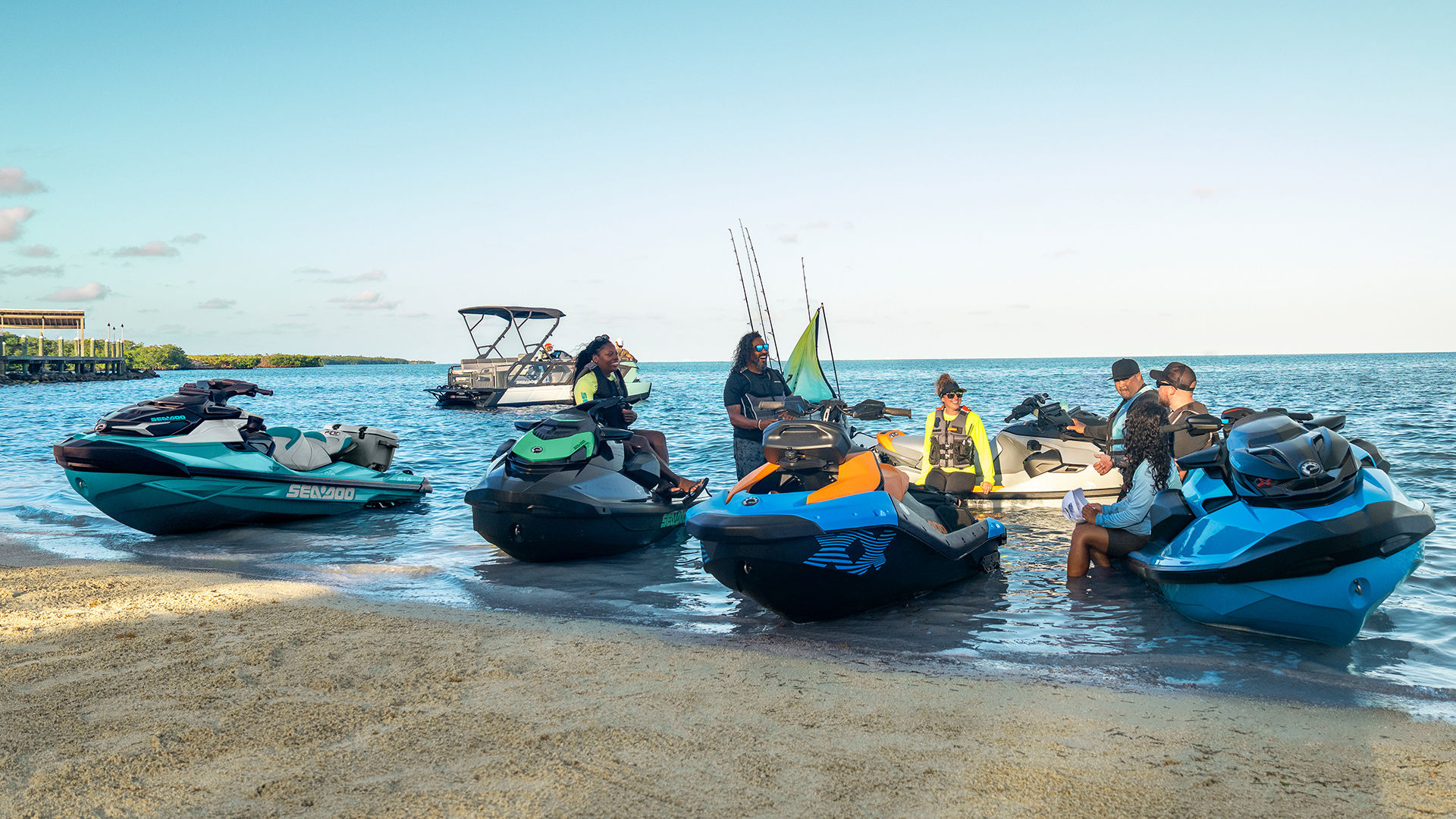 A group of friends taking a break near their Sea-Doo personal watercraft and pontoon boat.