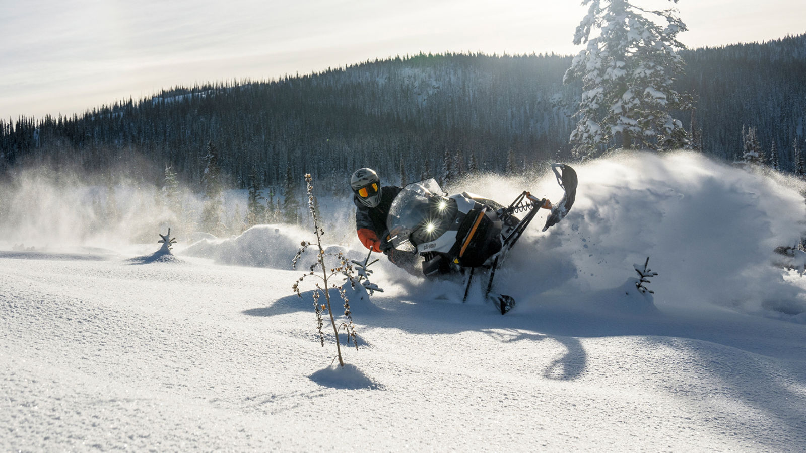 A rider leaving powder snow behind his Ski-Doo snowmobile on a mountain