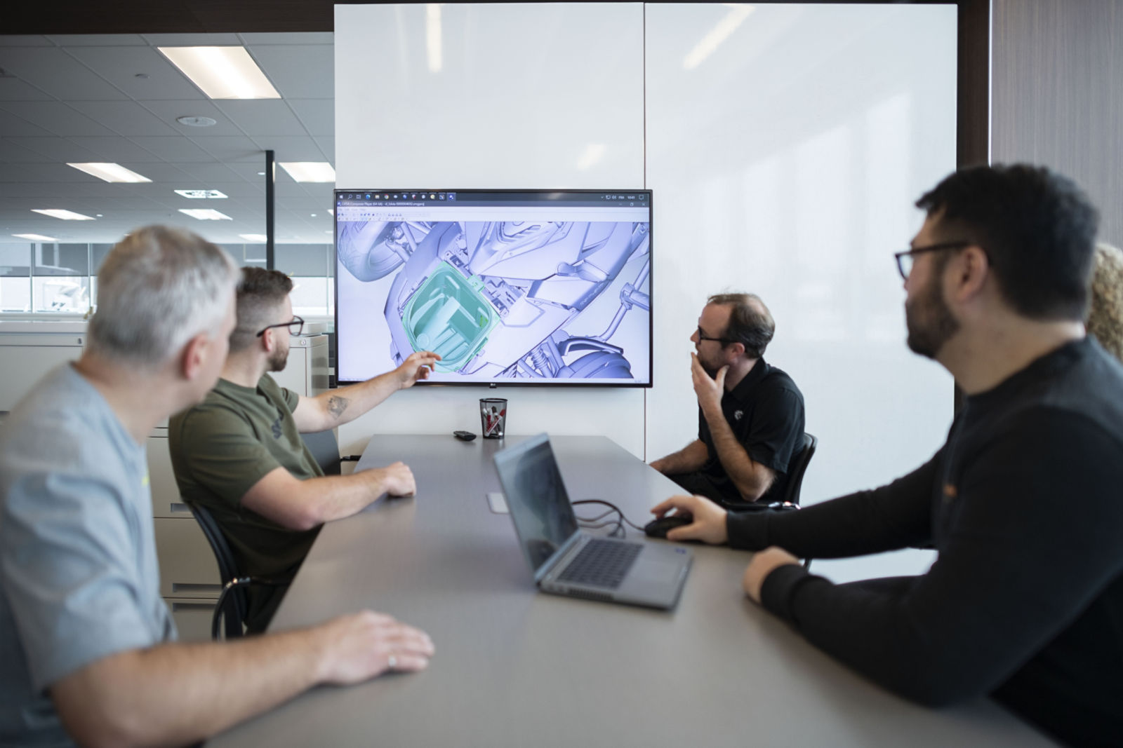 Grupo de hombres discutiendo durante una reunión sobre un proyecto alrededor de una mesa.