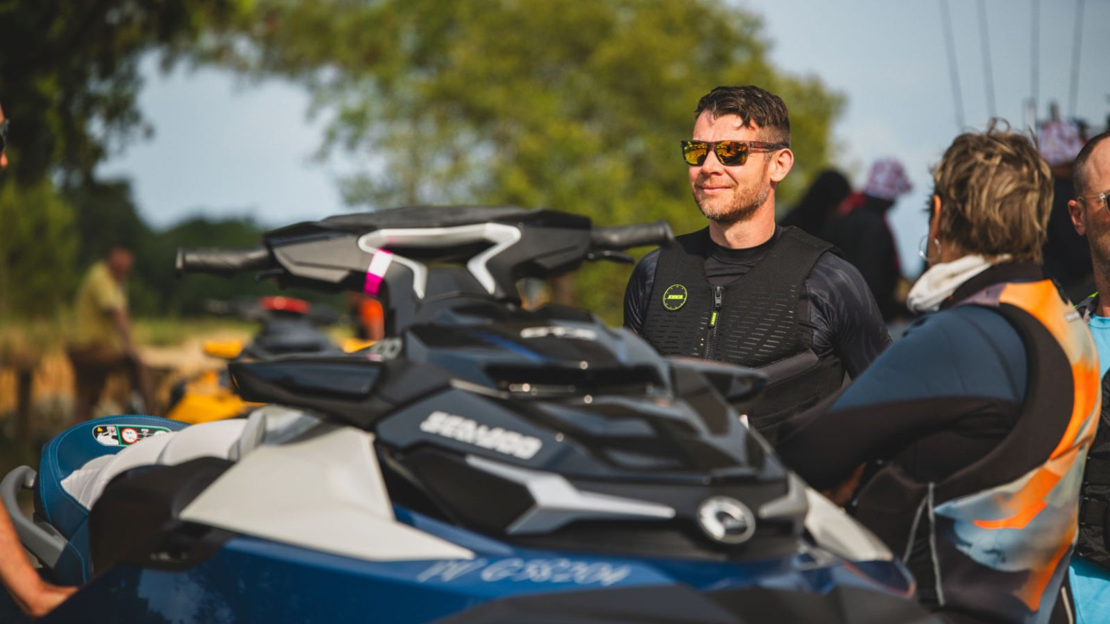 Deux personnes à côté du logo du Sea-Doo Social Club près des palmiers