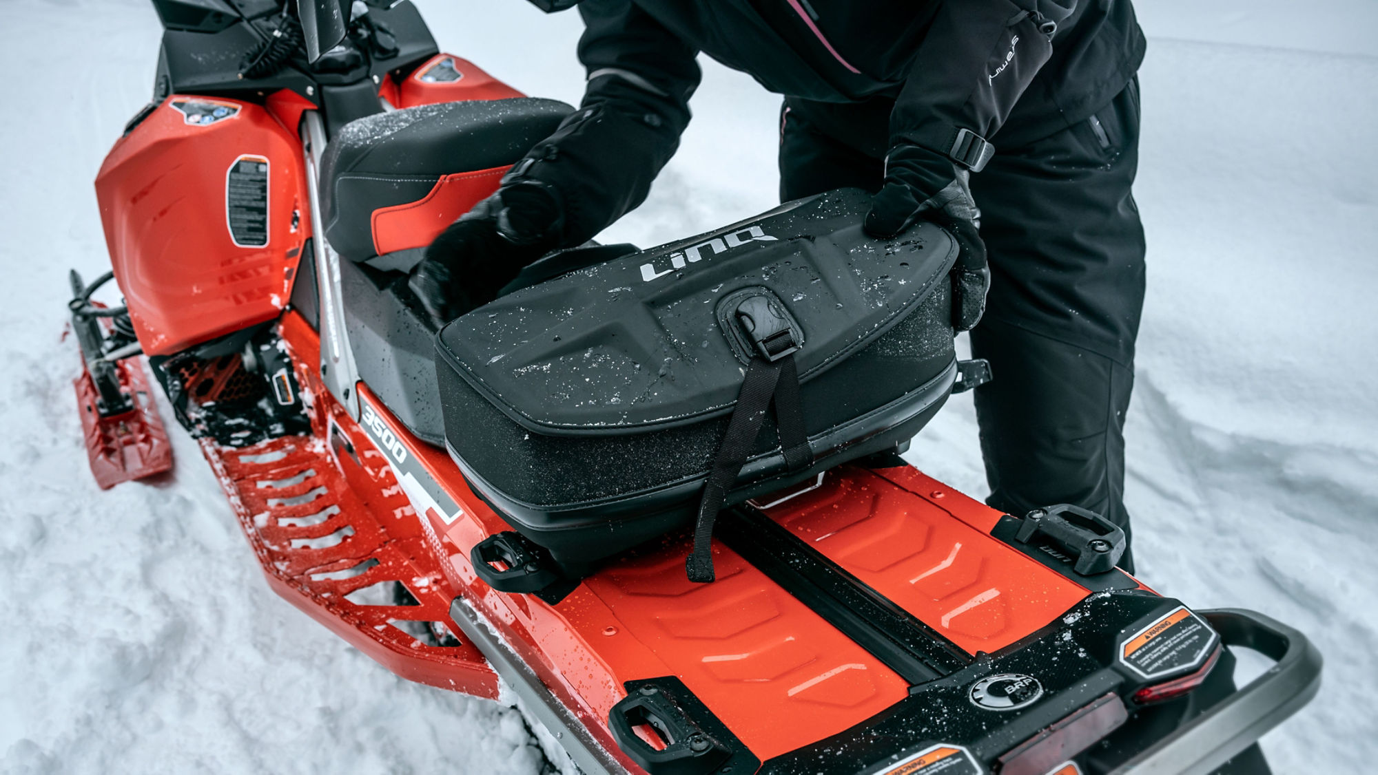 Rider installing a LinQ storage on a Lynx snowmobile