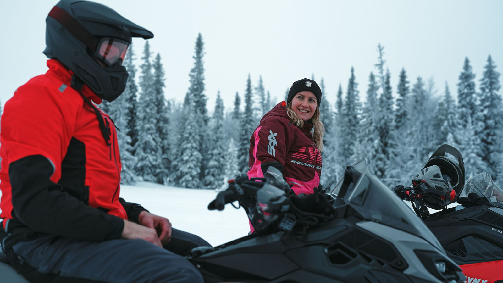Kaksi kuljettajaa juttelemassa Lynx-moottorikelkkojen päällä