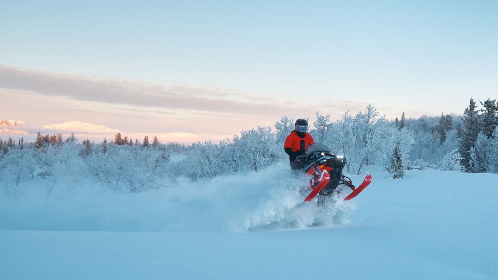 A snowmobiler riding the 2026 Lynx Commander RE snowmobile on a snow-covered mountain.
