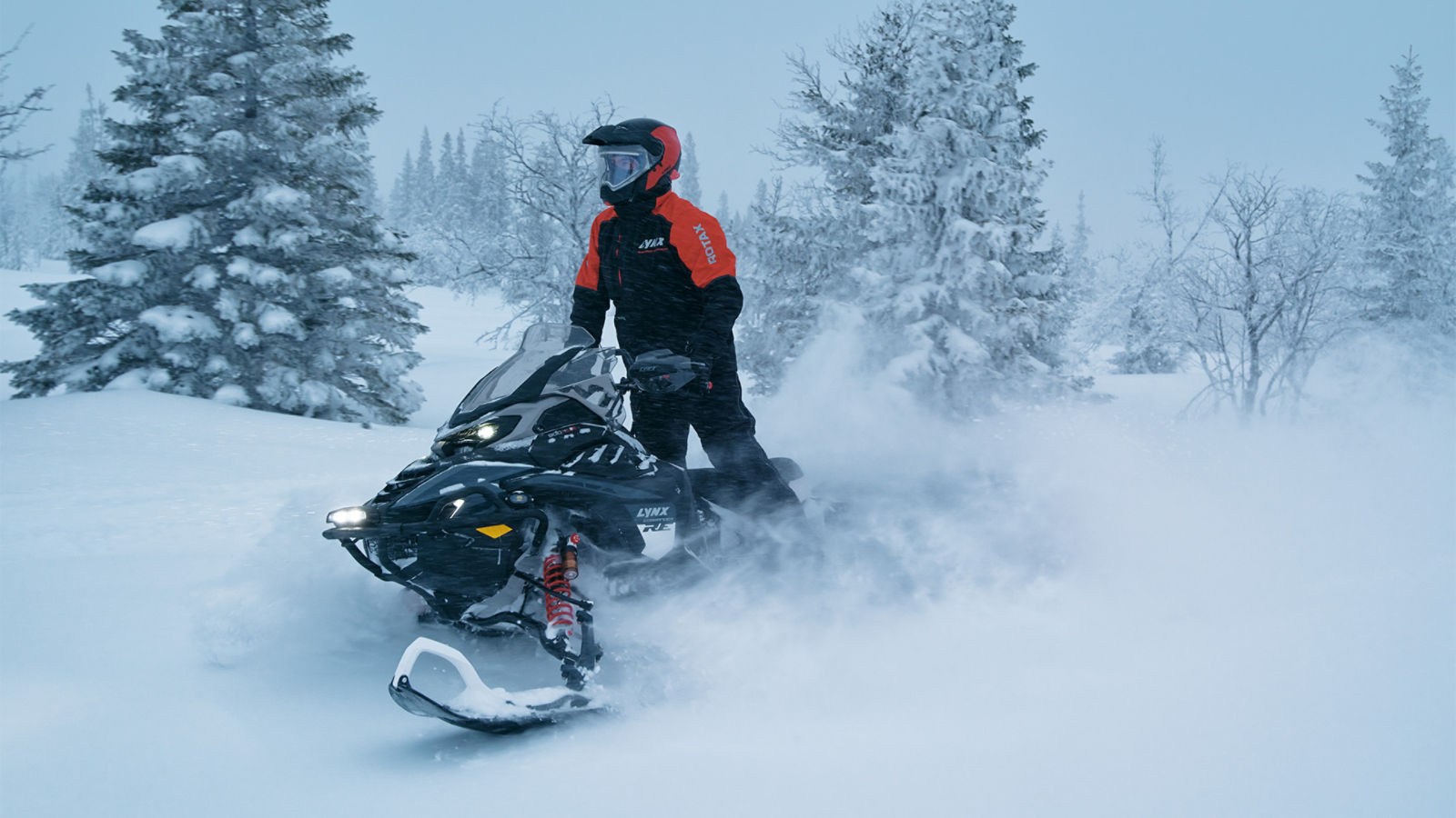 Rider riding a 2027 Lynx Xterrain RE snowmobile in a snow-filled forest