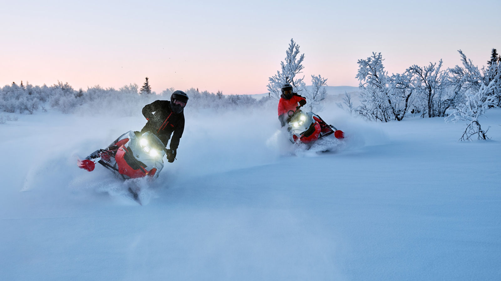 Deux motoneigistes qui zigzaguent sur un champ enneigé