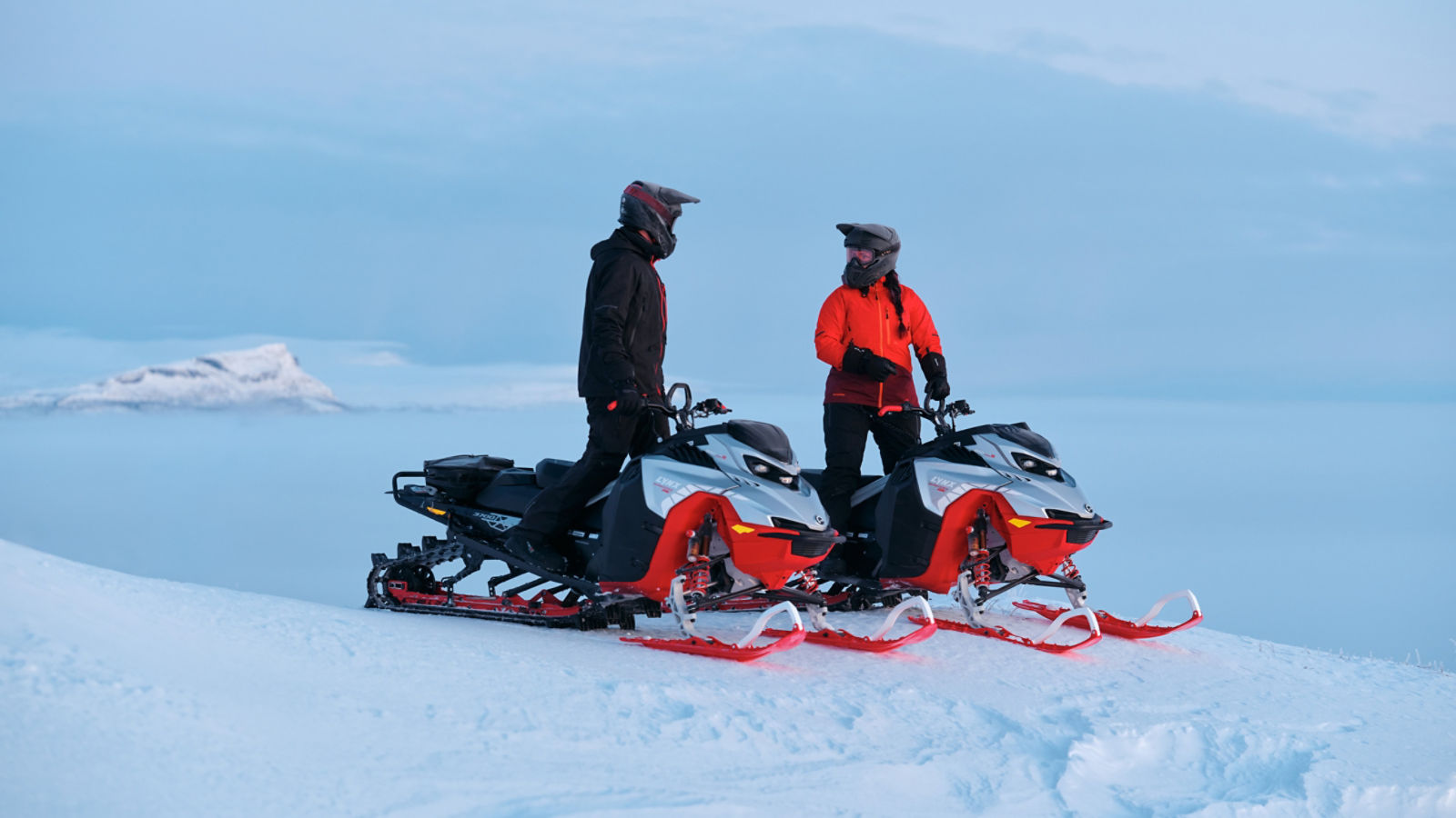 To Lynx Shredder RE-snøscootere parkert på toppen av en bakke.