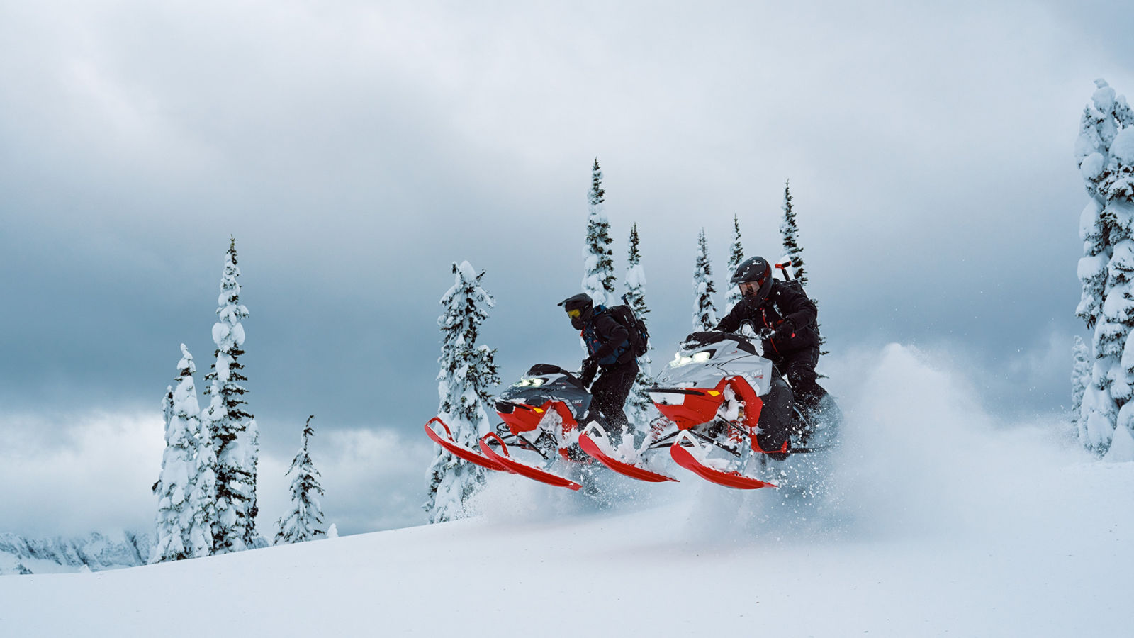 Two Lynx Shredder snowmobiles jumping off a snowy hill
