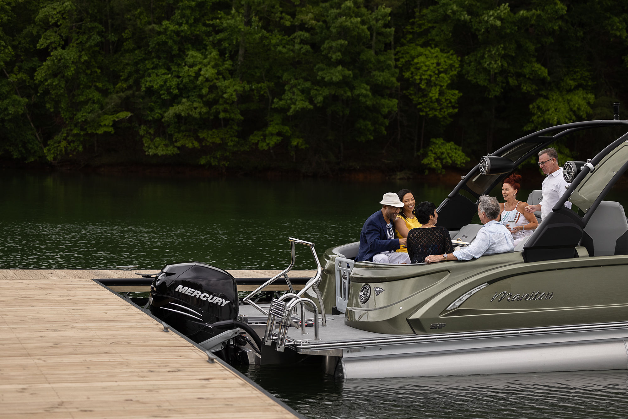 Family sitting in a docked Manitou pontoon boat