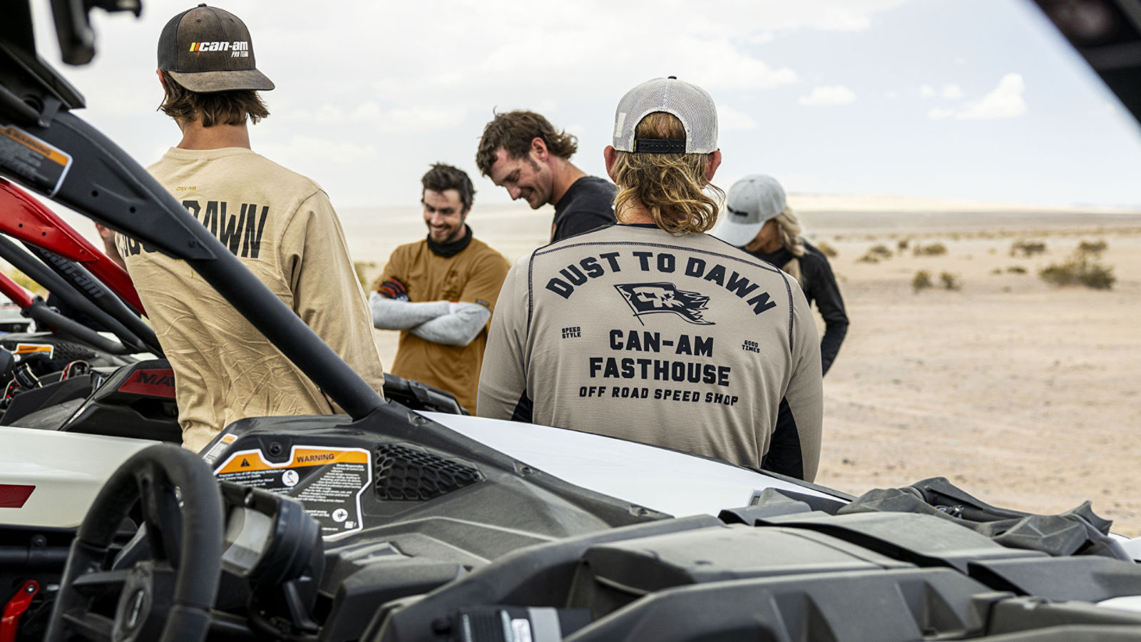 Can-Am rider placing their right leg down and up into red and black Can-Am mud apparel