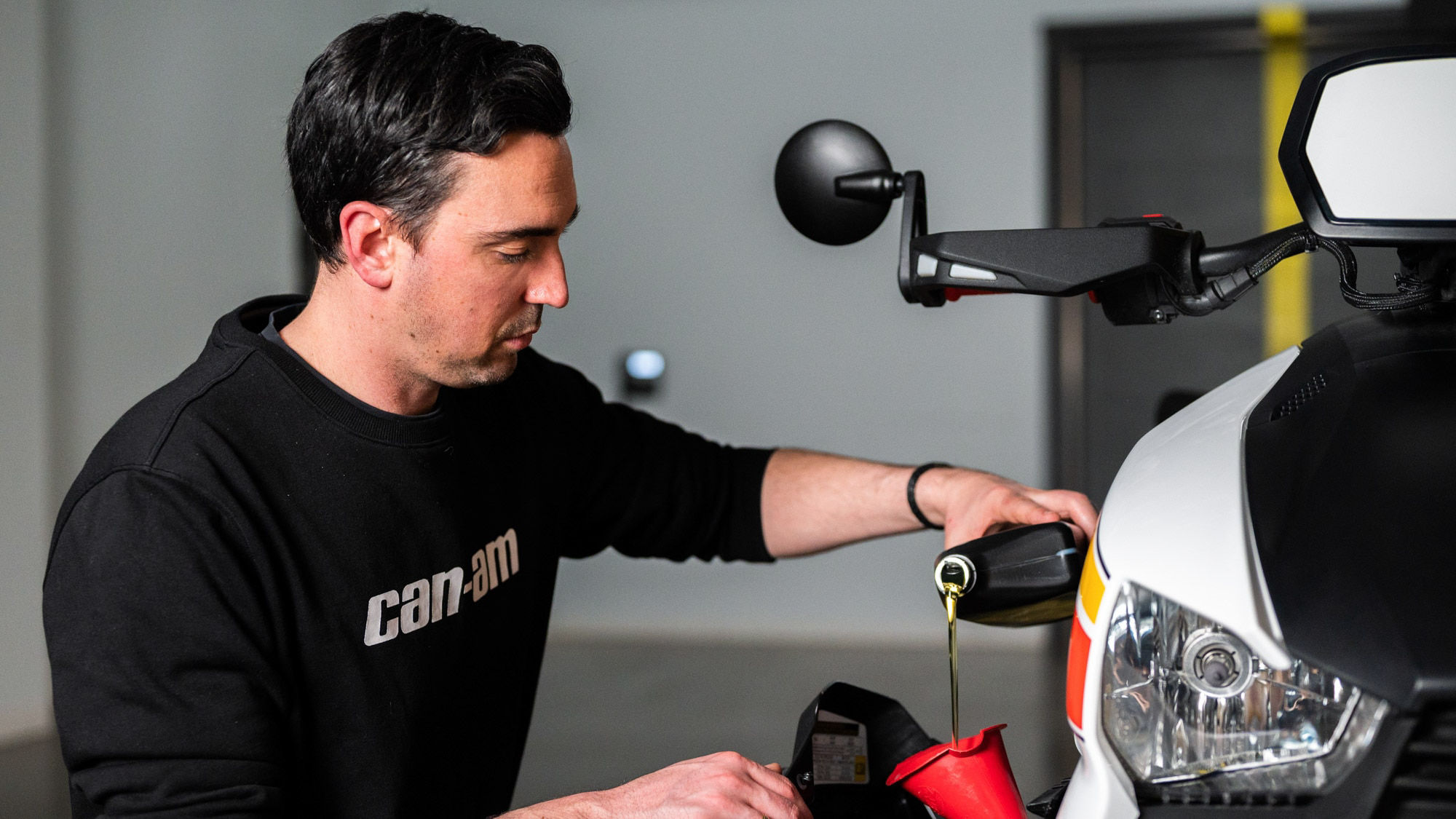 Pilote qui met de l'huile dans son véhicule 3-roues de Can-Am