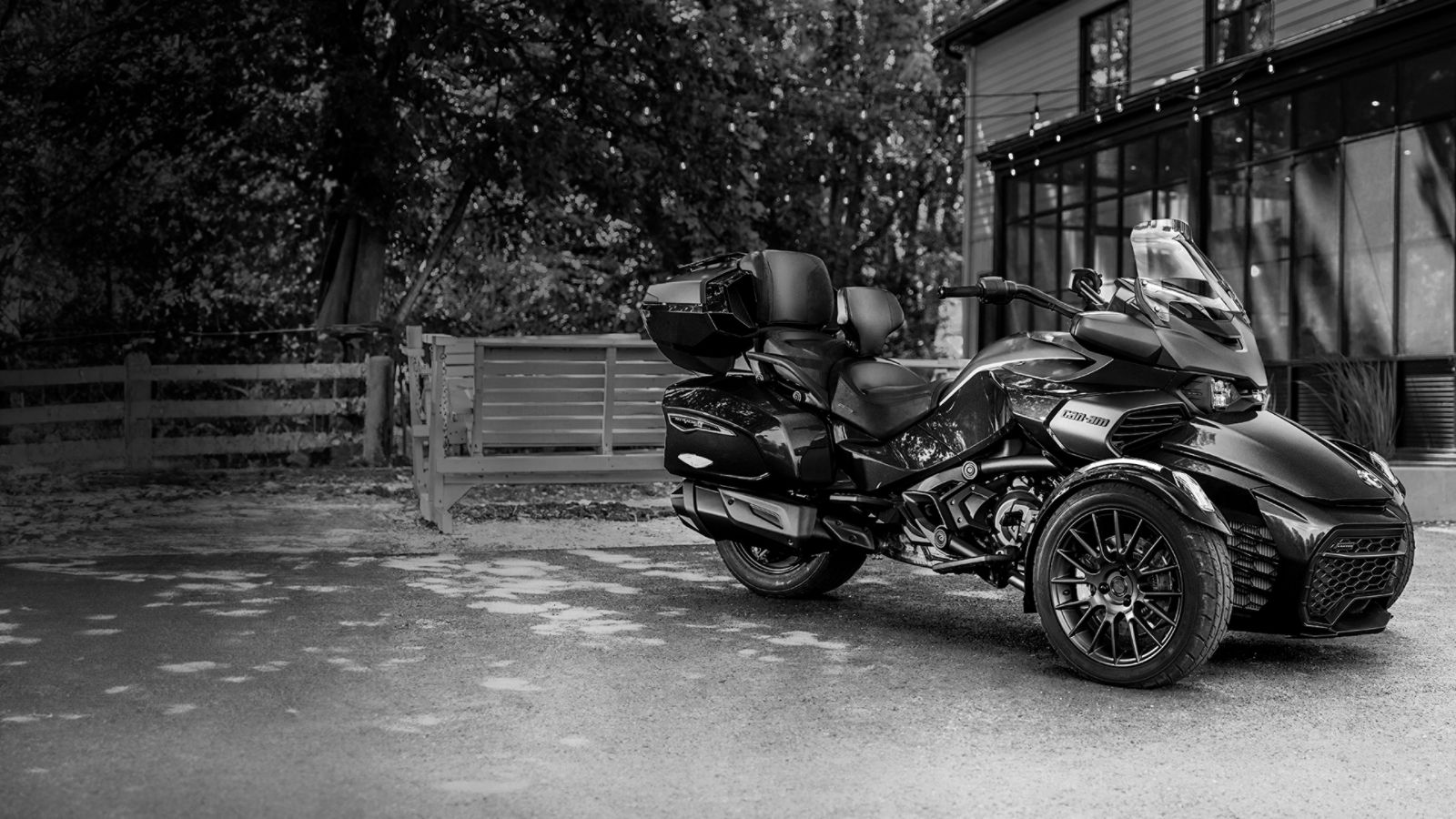 Black-and-white photo of a Can-Am Ryker 2025 3-wheeler parked in front of a country house