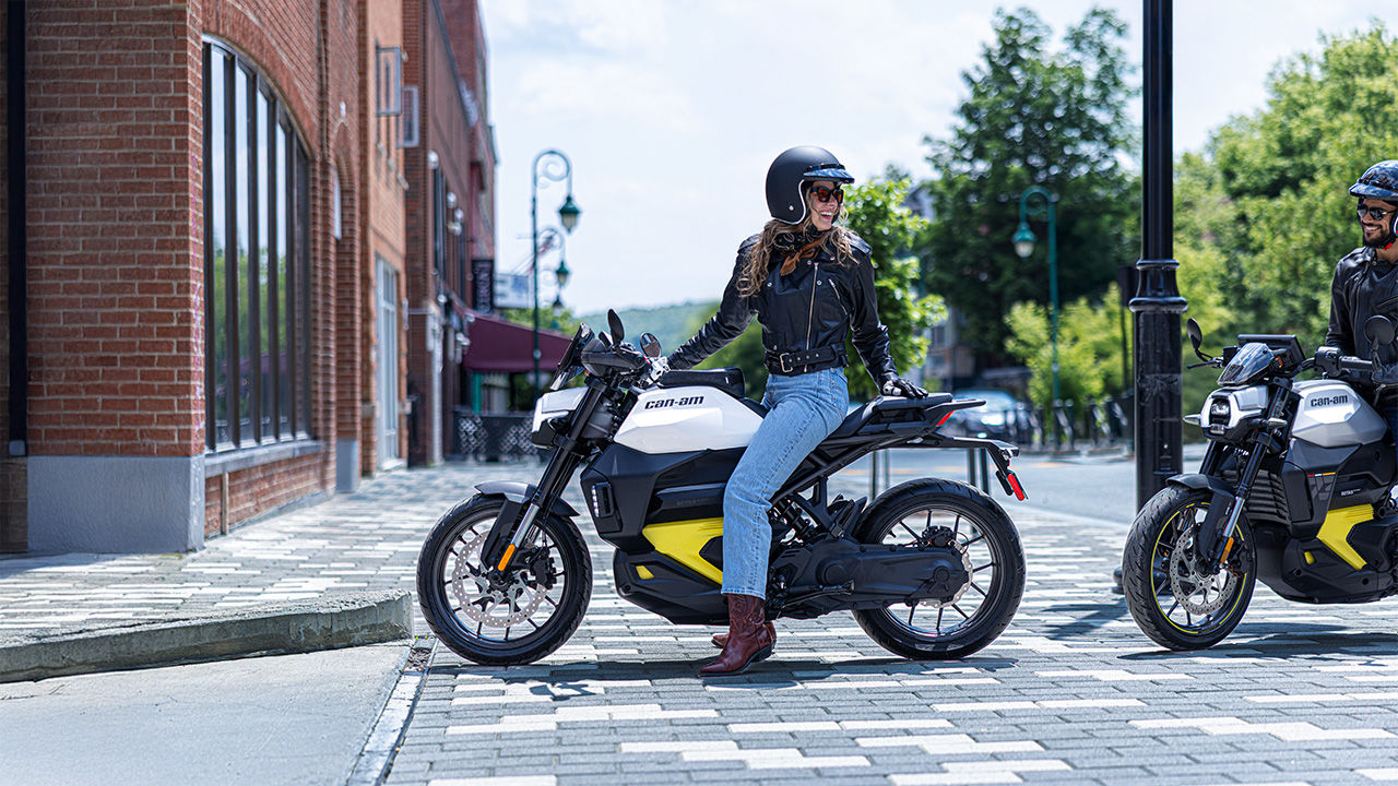 A man and a woman happy to ride their Can-Am electric motorcycle
