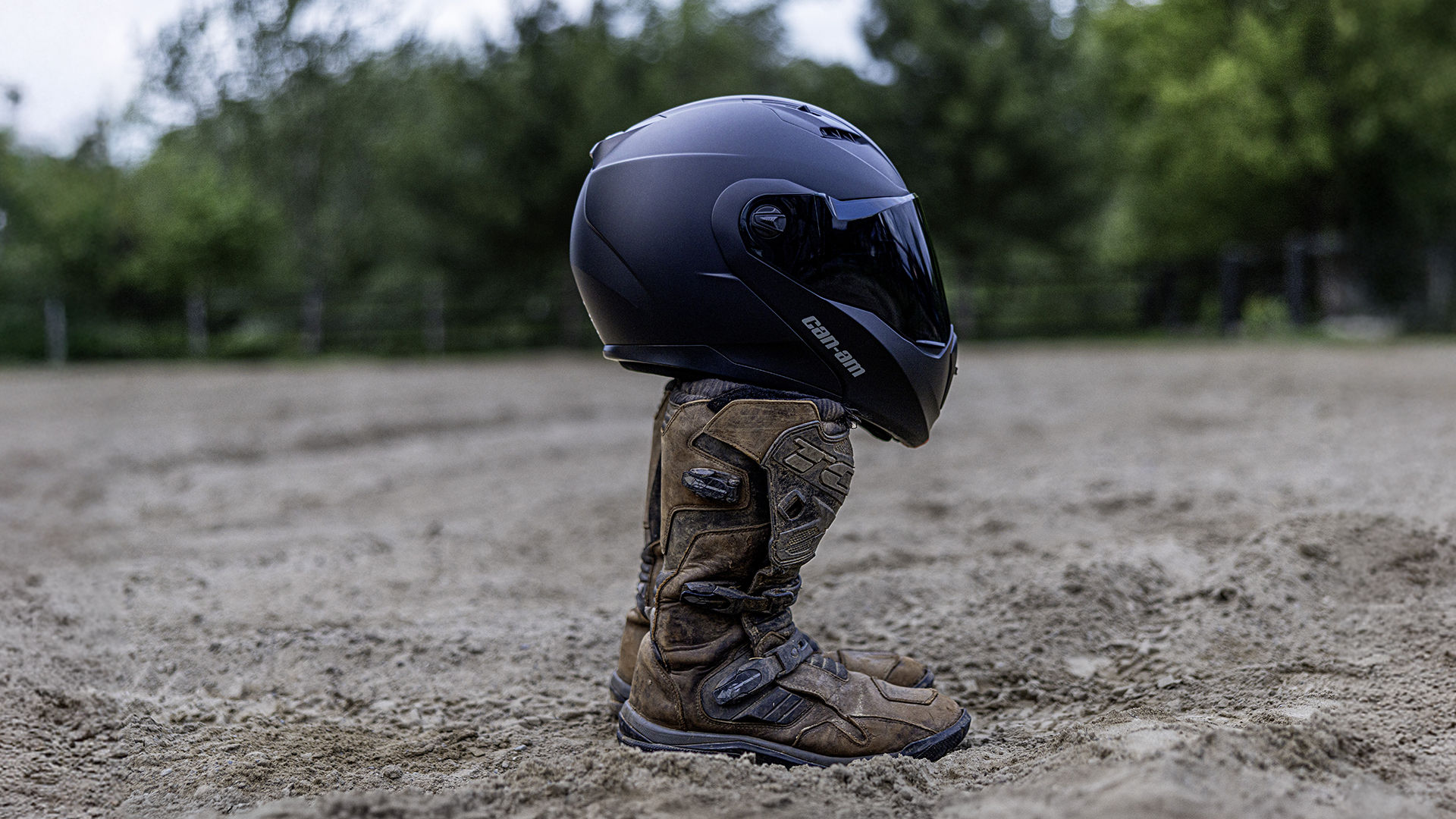 A Can-Am motorcycle helmet placed on a pair of boots