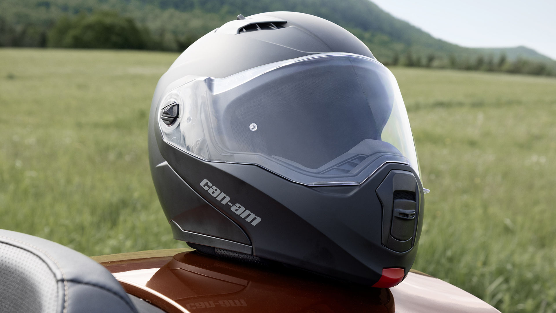 Rider securing their helmet while sitting on their Can-Am 3-wheel vehicle