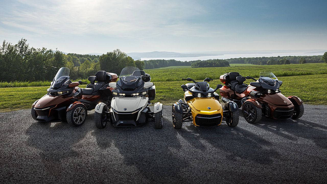 Various models of three-wheeled Can-Am vehicles parked near a field