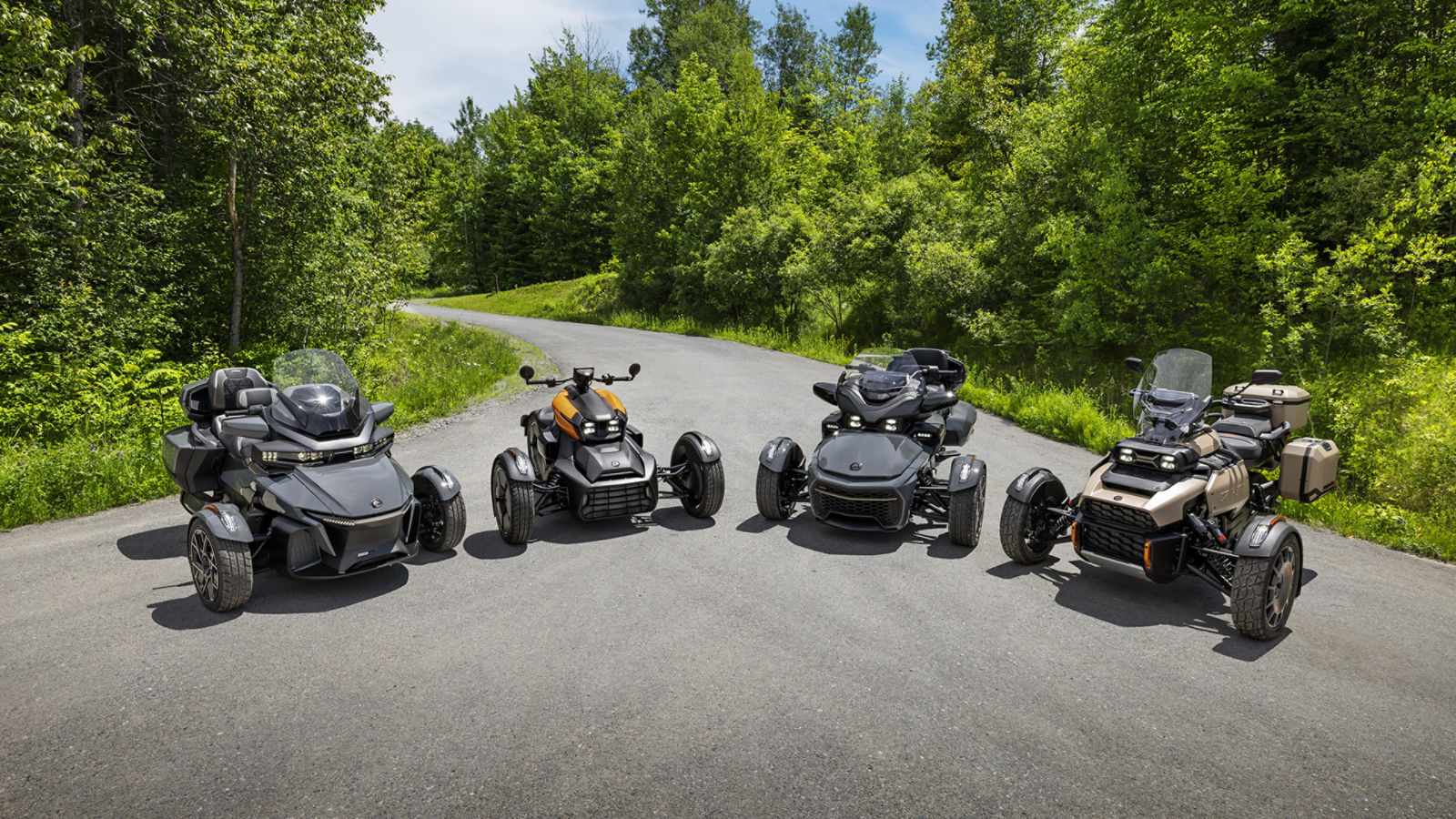 La famille de trois roues Can-Am 2027 stationnés côte à côte sur une route sinueuse bordée d’arbres