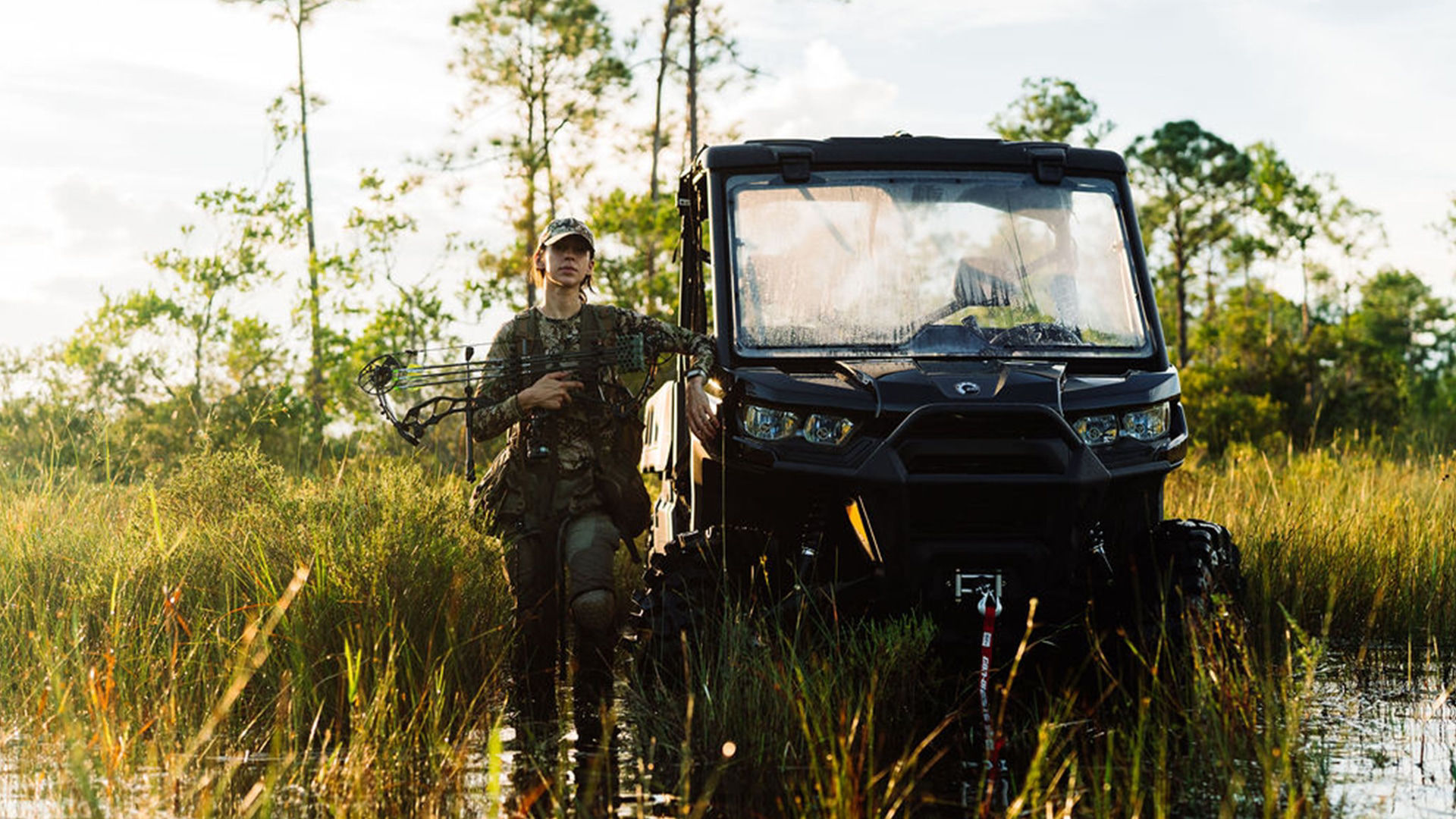 A woman with her crossbow, posed next to her Can-Am side-by-side