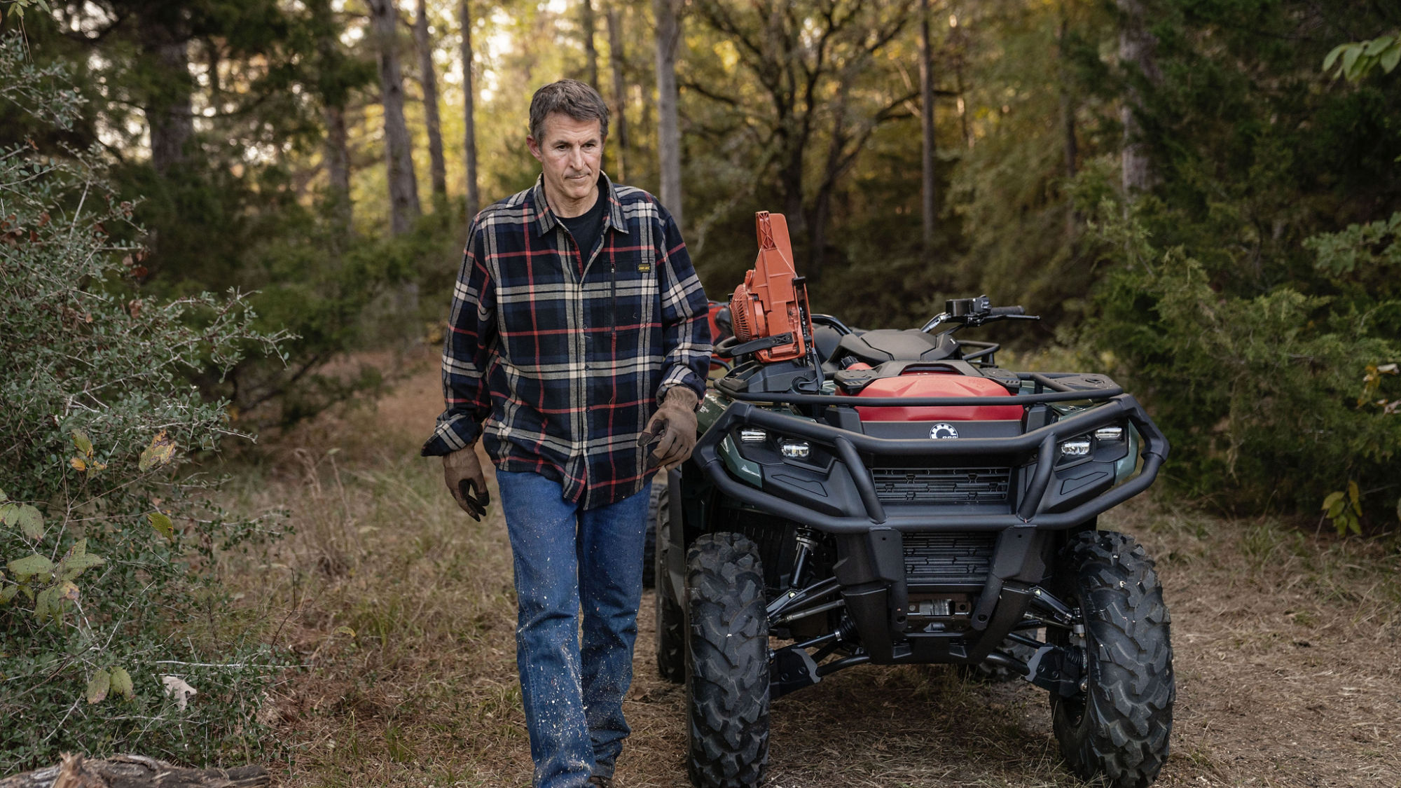 Hombre que camina delante de un Can-Am Outlander Pro equipado con accesorios de trabajo
