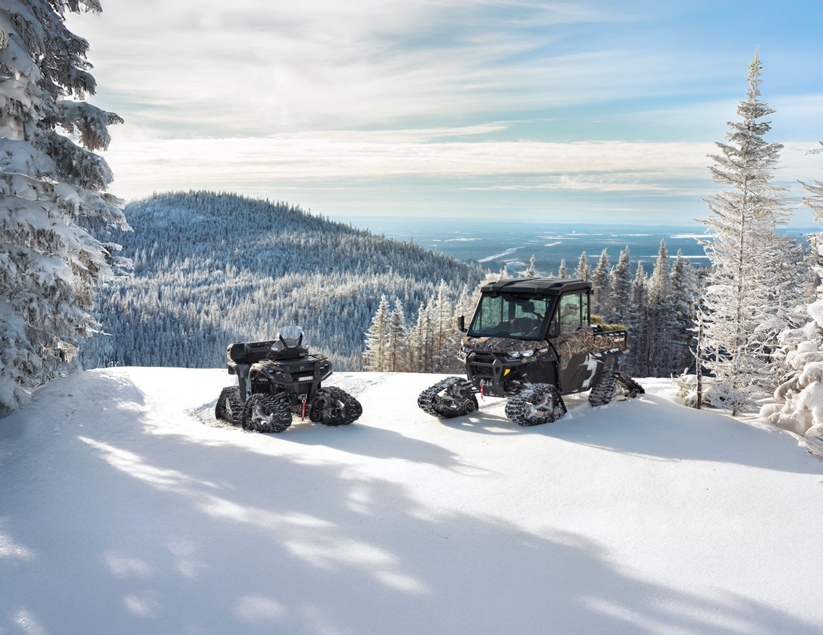 A Can-Am ATV and SxS with tracks on a snow-covered mountain