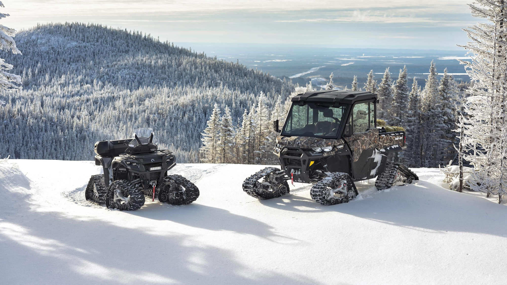 Un ATV y un SxS Can-Am con orugas en una montaña nevada
