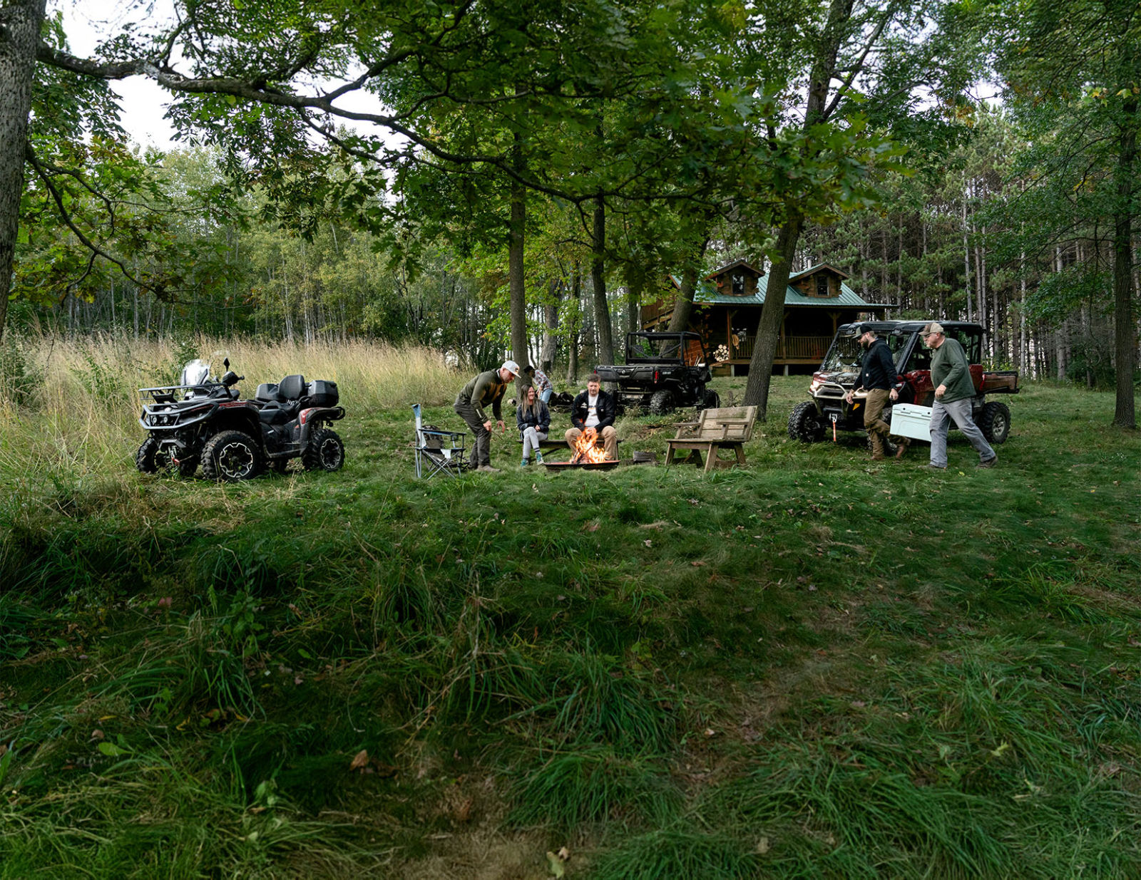 A group of friends surrounded by Can-Am all-terrain and side-by-side vehicles in the forest