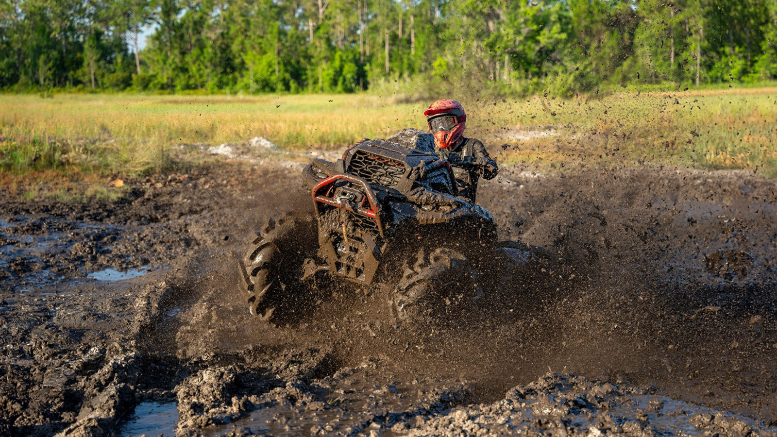 A Can-Am Outlander X mr ATV riding through mud