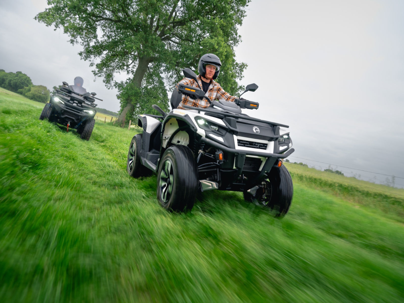 Zwei Can-Am Outlander Electric Quads rasen durch ein Feld