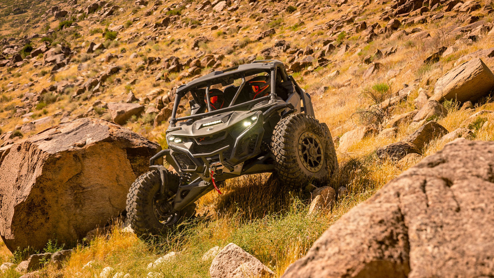 Two riders in a side-by-side Can-Am descending a rocky slope
