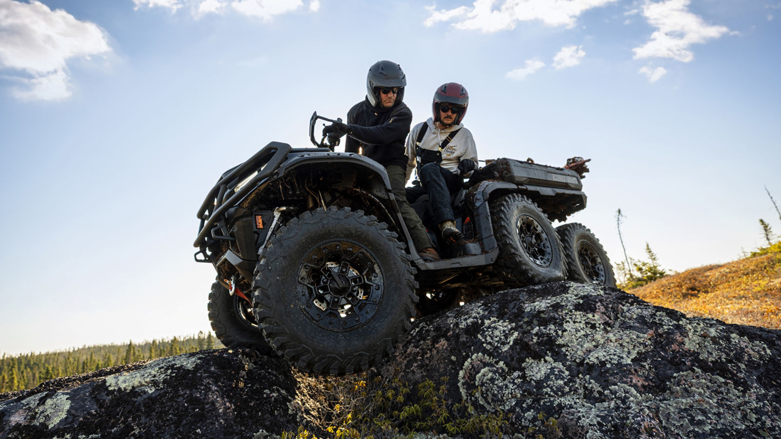 Two men on a Can-Am 6-wheel ATV riding over rocks 