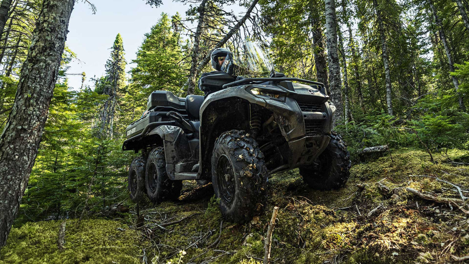 A Can-Am 6-wheel ATV riding through the forest on rough terrain
