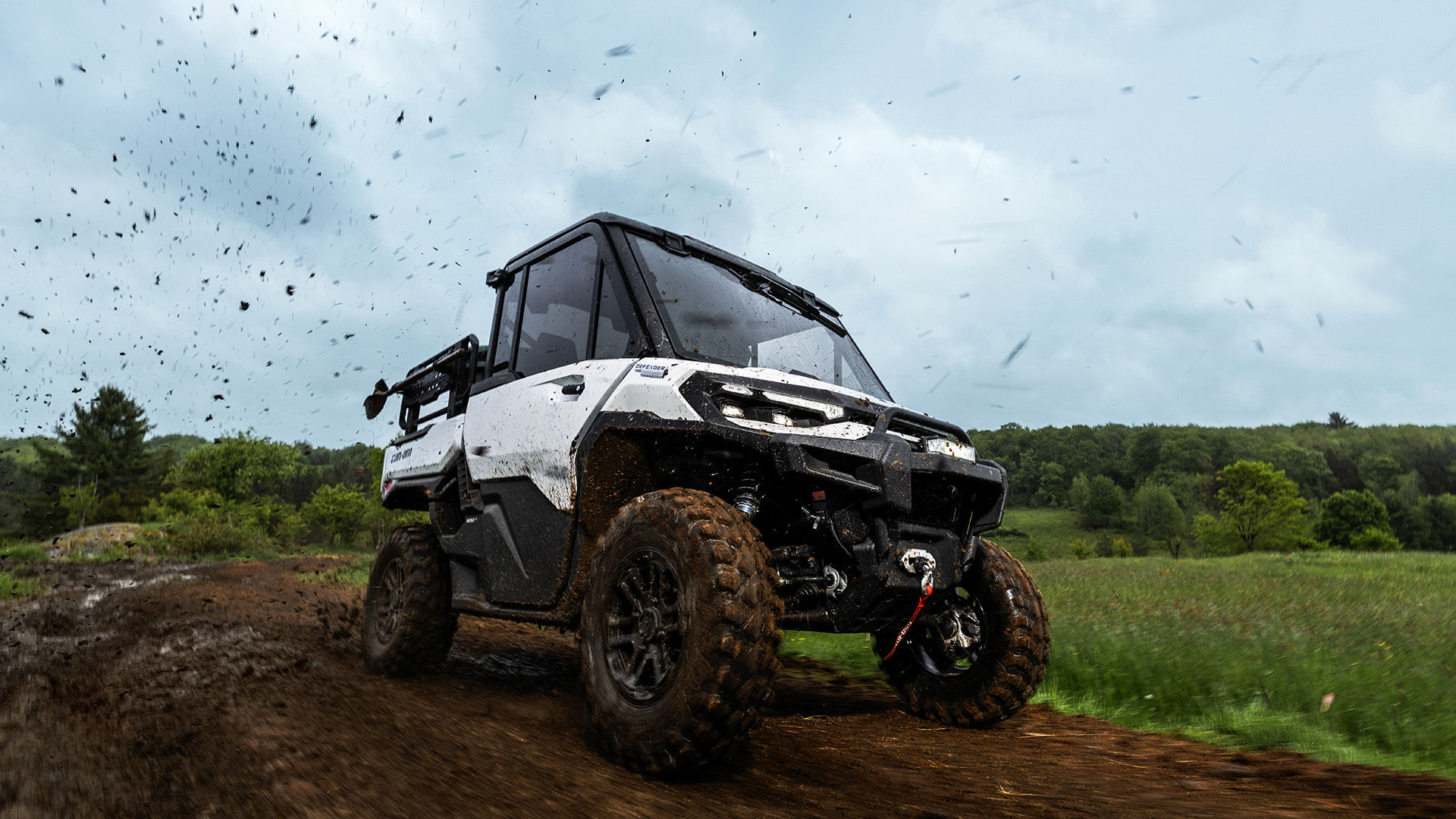 2026 Can-Am Defender HD11 Hybrid White driving on a dirt road