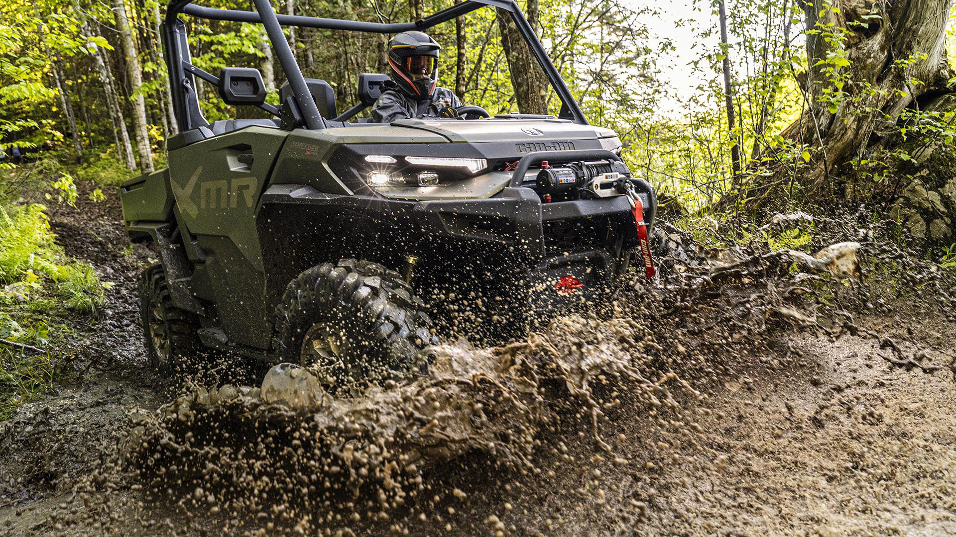 A 2026 Can-Am Defender X MR side-by-side making a splash in the mud