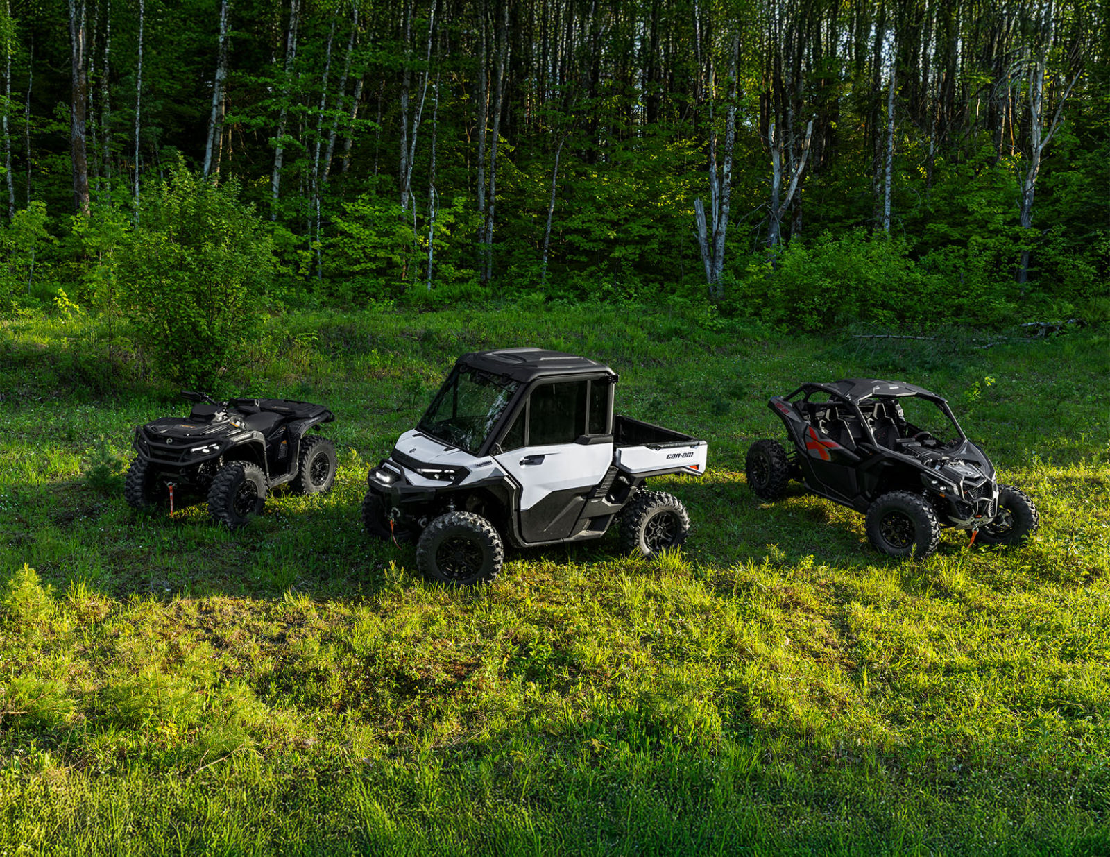 Two 2026 Can-Am side-by-side vehicles and one ATV near a forest