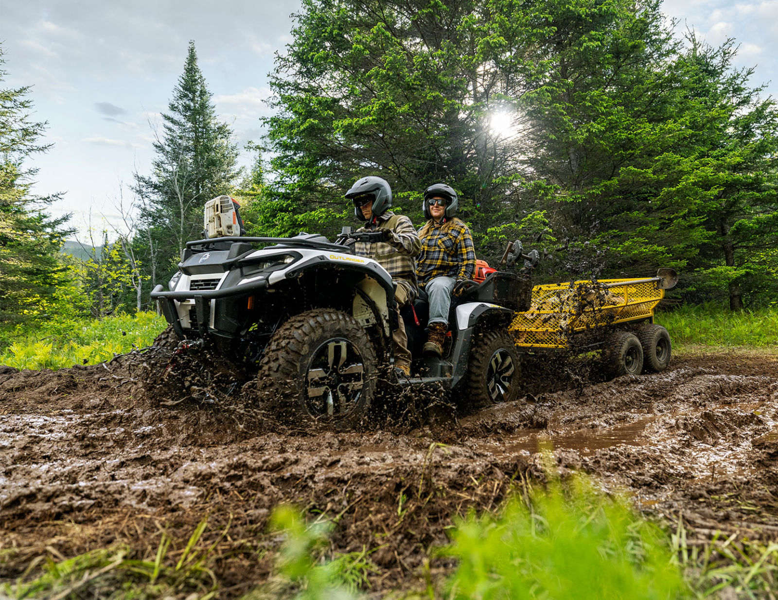A couple on an all-new Can-Am Outlander Electric 2026 designed for work, passing through mud